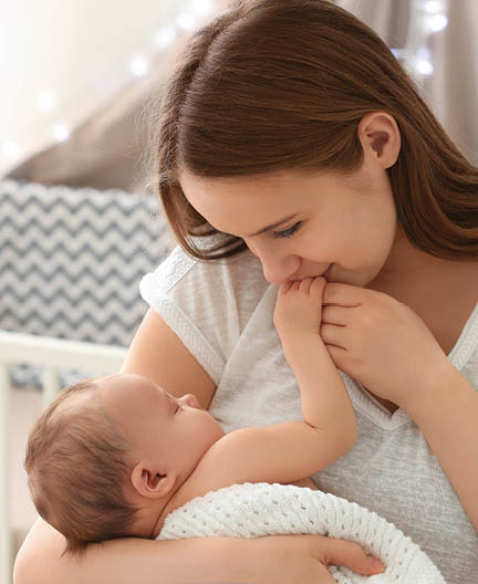 Mother holding sleeping newborn at home