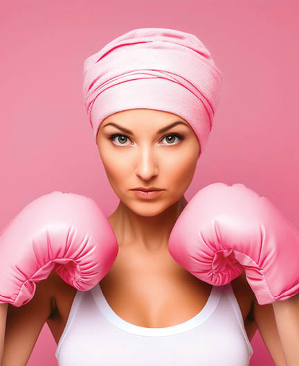 Female cancer patient with pink headscarf and boxing gloves in her hands as a sign of fight and strength. Concept of fighting and beating cancer.