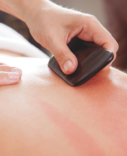 Large bone scraper tool being used ruing a guasha acupuncture treatment