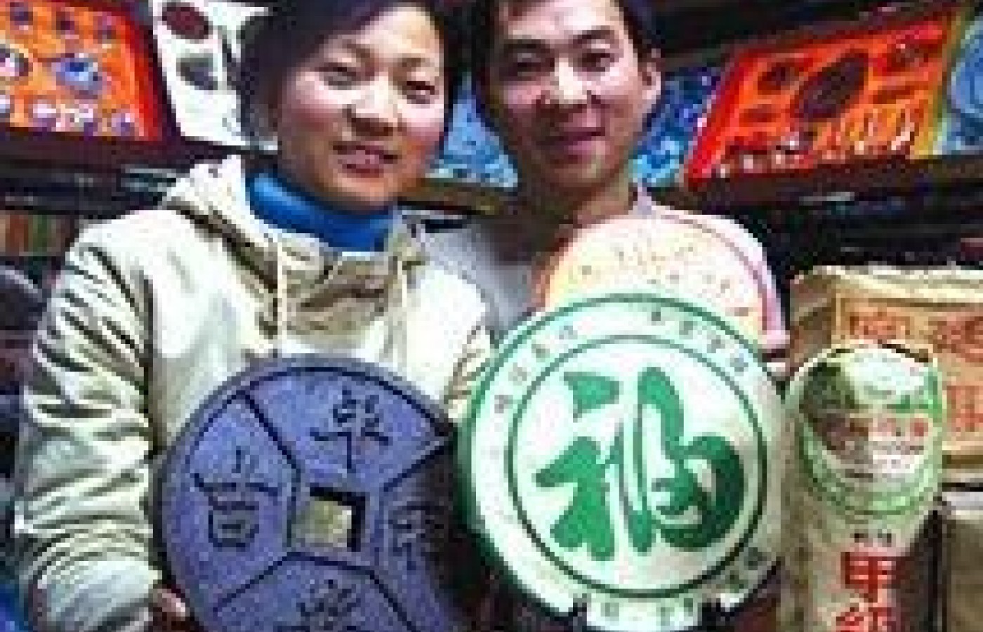 Yunnan couple displaying bricked pu cha (shu style) in tea shop.